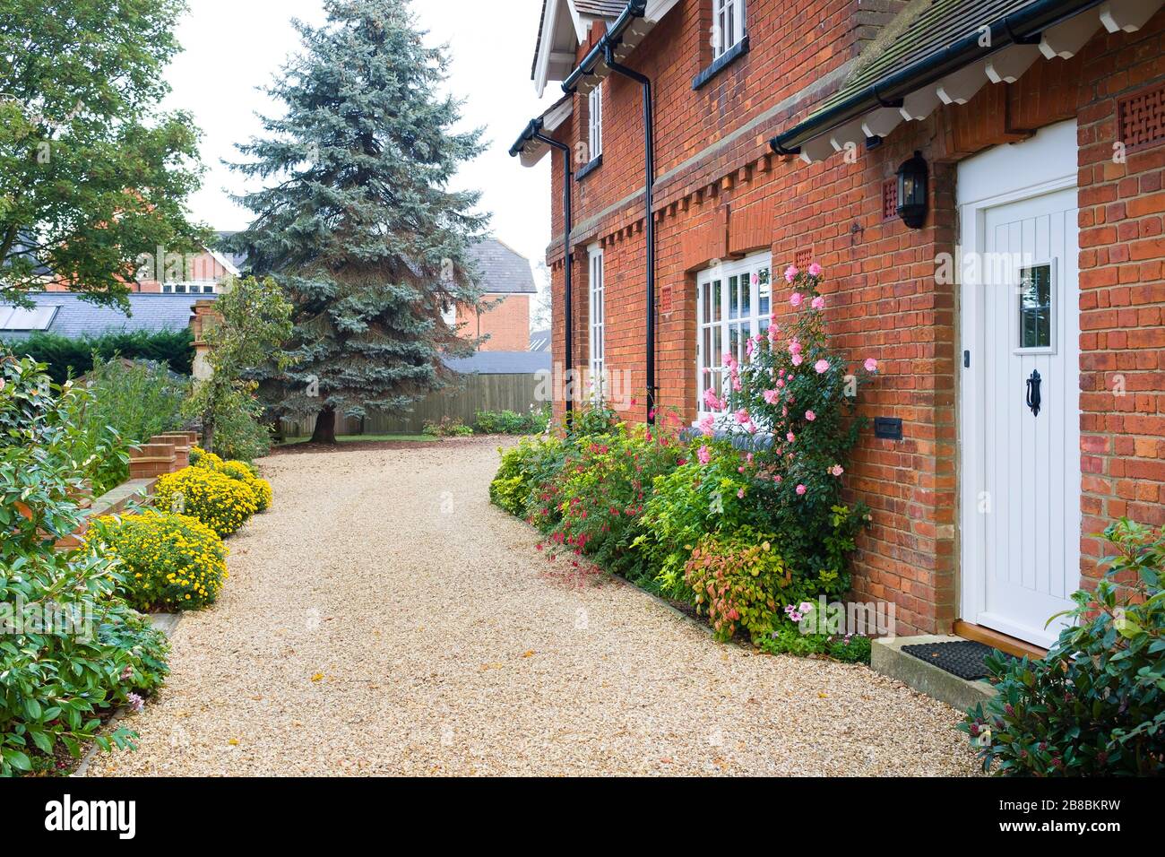 Maison de campagne anglaise et jardin en automne avec une allée de gravier. La maison est de l'époque victorienne, avec des bordures fleuries remplies d'arbustes et de vivaces Banque D'Images