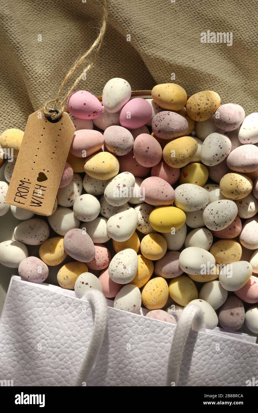 Plusieurs oeufs de Pâques colorés au chocolat sur la plaque ronde, sac cadeau en toile, bouquet de fleurs bleu printemps. Mise à plat, vue de dessus. Pâques, symbole du printemps Banque D'Images