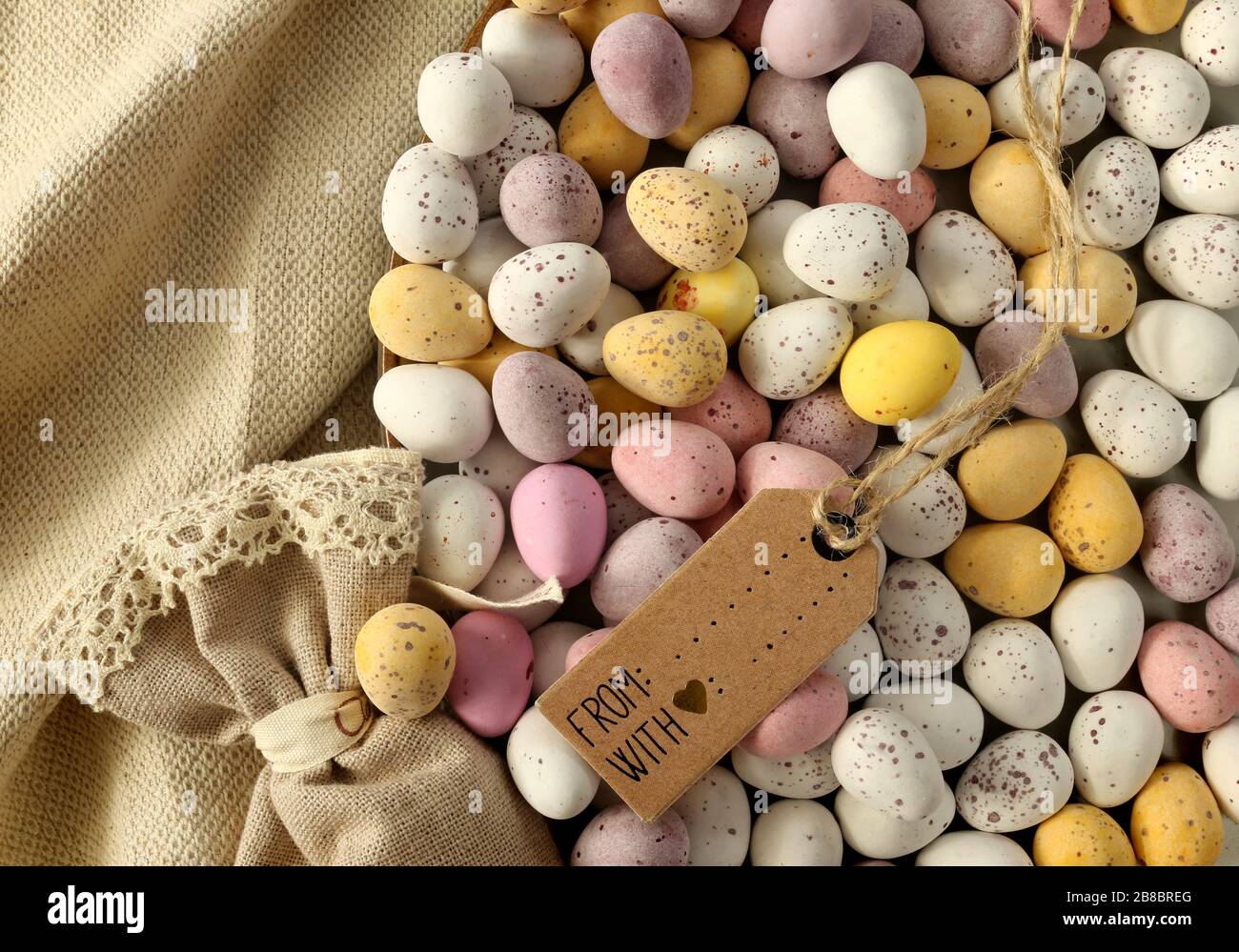 Plusieurs oeufs de Pâques colorés au chocolat sur la plaque ronde, sac cadeau en toile, bouquet de fleurs bleu printemps. Mise à plat, vue de dessus. Pâques, symbole du printemps Banque D'Images