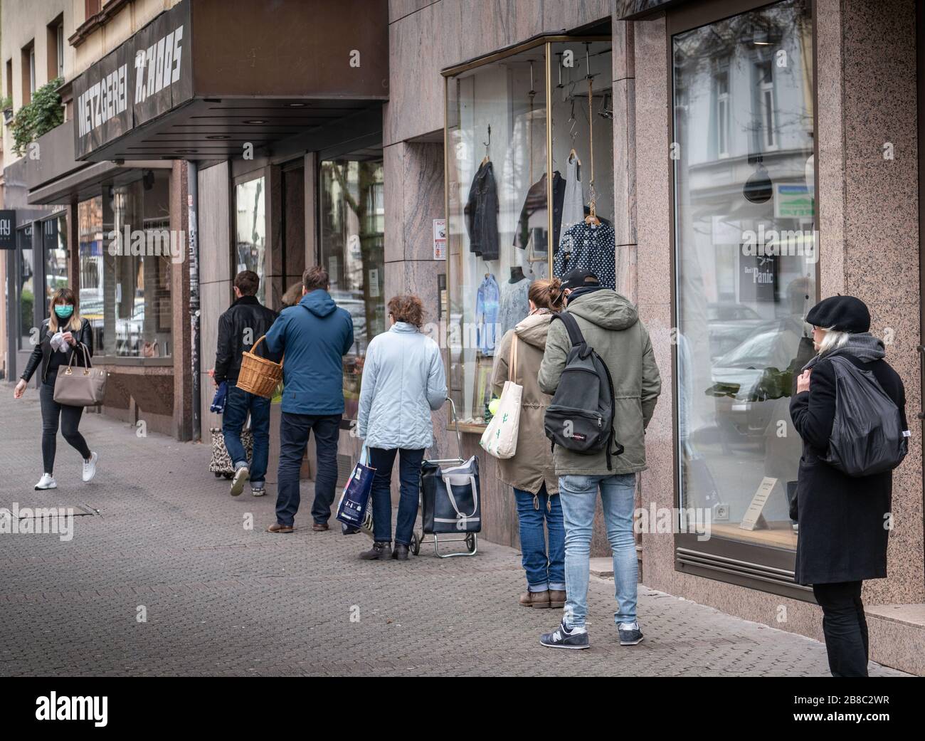 21 mars 2020, Hessen, Frabkfurt/Main: Les clients attendent à une distance raisonnable devant un magasin de boucher sur Berger Straße. Photo: Frank Rumpenhorst/dpa Banque D'Images