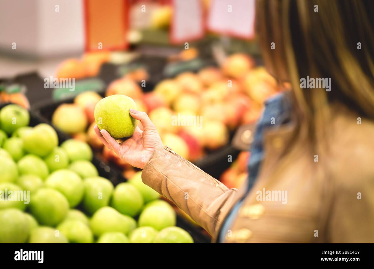 Shopping pour des fruits et des aliments sains dans le supermarché. Femme de fitness sur alimentation biologique faisant des provisions. Femme achetant, tenant et choisissant la pomme fraîche. Banque D'Images