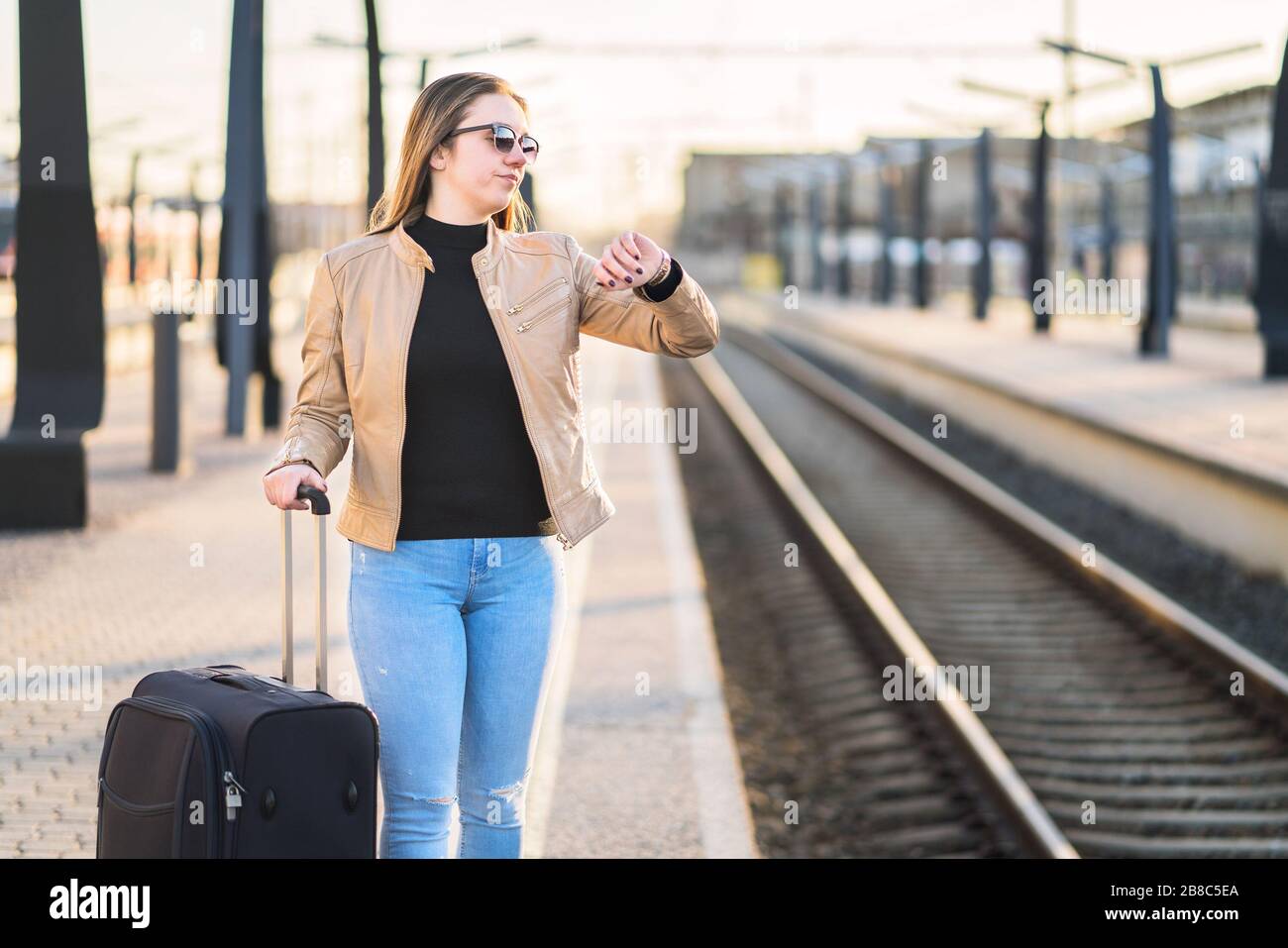 Une femme mécontente et frustrée qui regarde l'heure et regarde à la gare. Passager en colère à la plate-forme ferroviaire. Banque D'Images