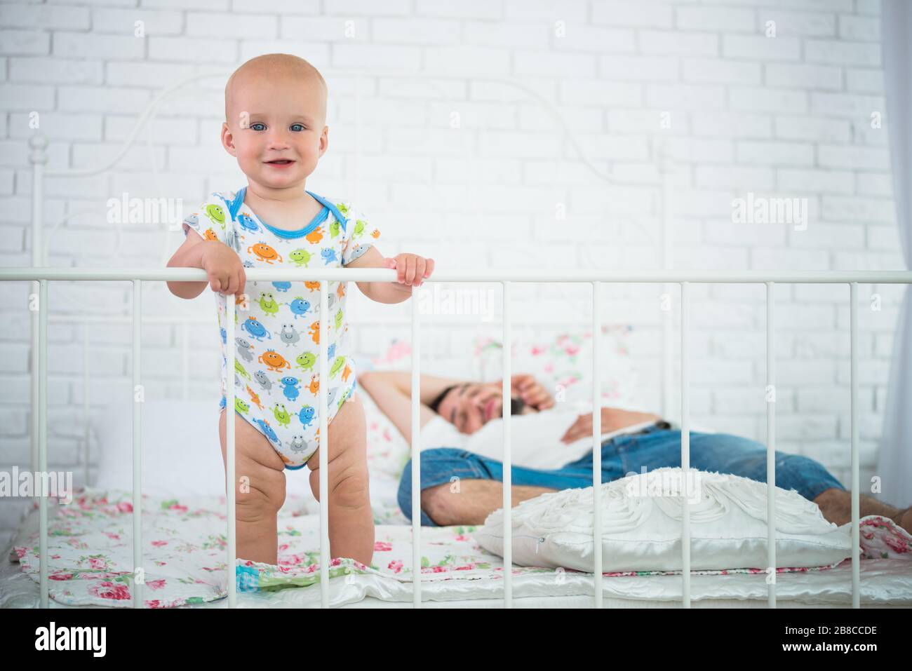 Le Joli Petit Bebe Est Debout Sur Le Bord Du Lit Qui Tient Sur La Tete De Lit Contre Le Fond De Ses Parents Dormant Concept De Fatigue Environ Photo Stock Le Joli Petit Bebe Est Debout Sur Le Bord Du Lit Qui Tient Sur La Tete De Lit Contre Le Fond De Ses Parents Dormant Concept De Fatigue Environ Photo Stock