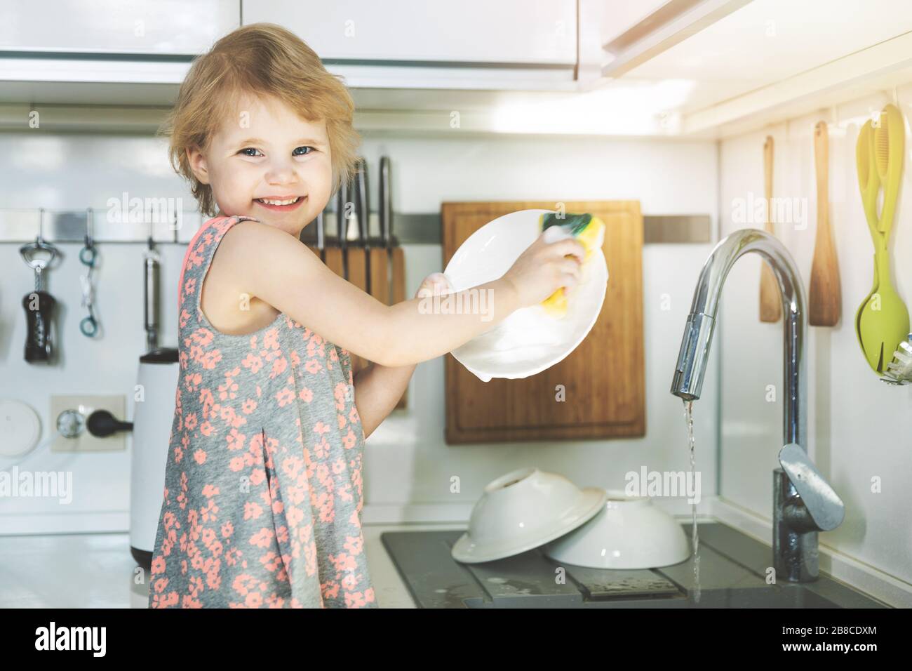 petite fille laver les plats avec éponge dans l'évier de cuisine à la maison Banque D'Images