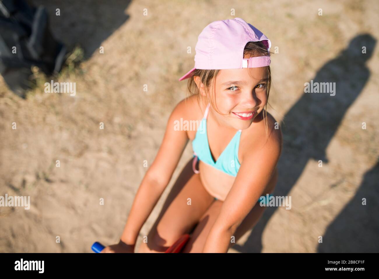 Une petite adorable fille joue sur un cheval jouet sur une aire de jeux près de la mer lors d'une chaude journée d'été ensoleillée pendant les vacances. Le concept de jeux pour enfants sur le Banque D'Images