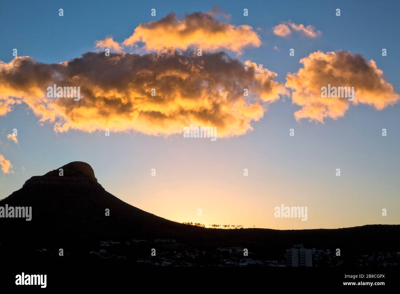 Lever du soleil sur la tête du Lion et signal Hill au Cap. Alors que le soleil se forme à l'horizon, la lumière fait tourner les nuages au-dessus d'un or brillant. Banque D'Images