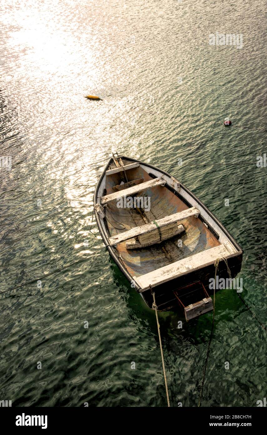 Amarré dans le port de Simon, un vieux bateau à ramer en bois baigne dans la lumière du soleil dorée de la fin de l'après-midi Banque D'Images