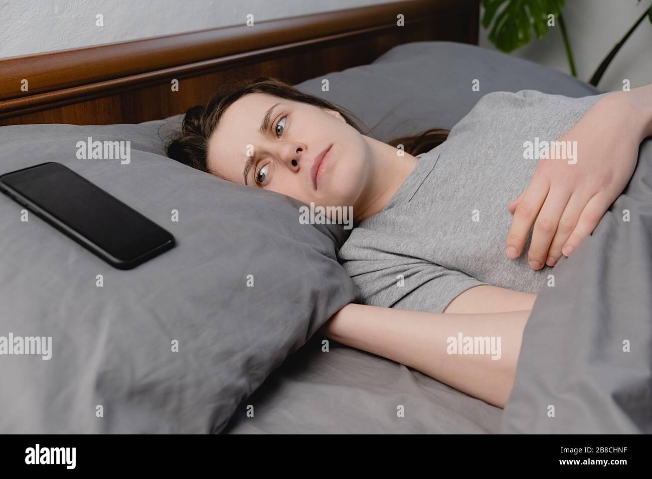 Gros plan bouleversé jeune femme couché dans le lit regardant sur smartphone se sent peur et peur, malheureux anxieux ayant des problèmes de relations difficultés Banque D'Images