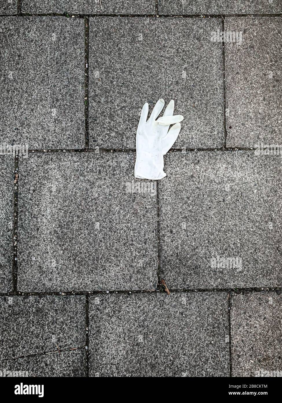 le gant en caoutchouc perdu sur le trottoir, symbole de la crise mondiale du covid 19 la pandémie mondiale au printemps 2020 Banque D'Images