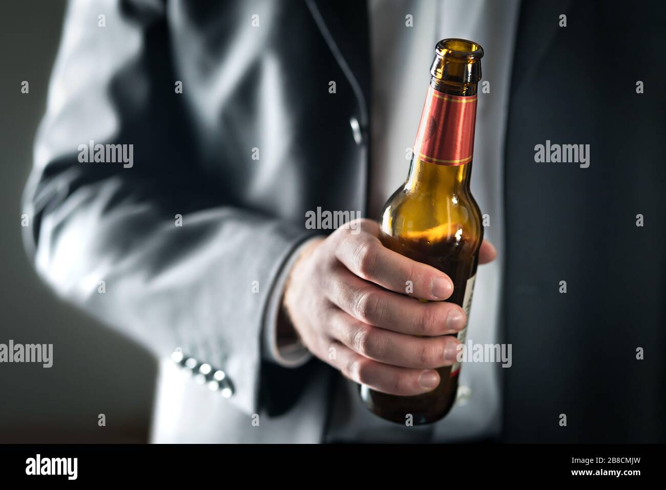 Homme d'affaires buvant de la bière. Homme d'affaires tenant une bouteille d'alcool. Un gars ivre avec un boobze. Fête au travail ou au bureau. Célébration du succès. Banque D'Images