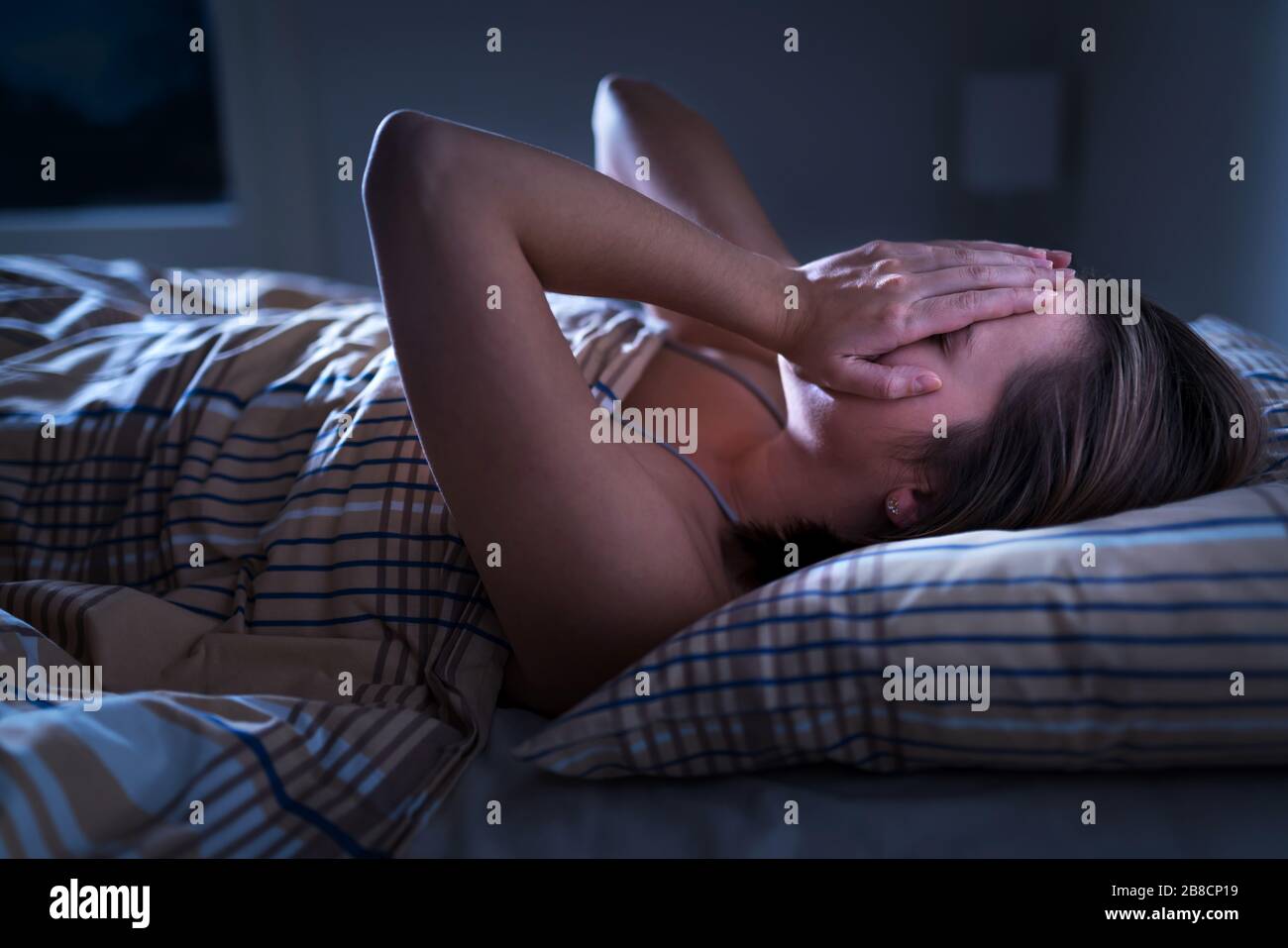 Insomnie, apnée du sommeil ou concept de stress. Femme éveillée et couvrant le visage au milieu de la nuit. Lady ne peut pas dormir. Banque D'Images