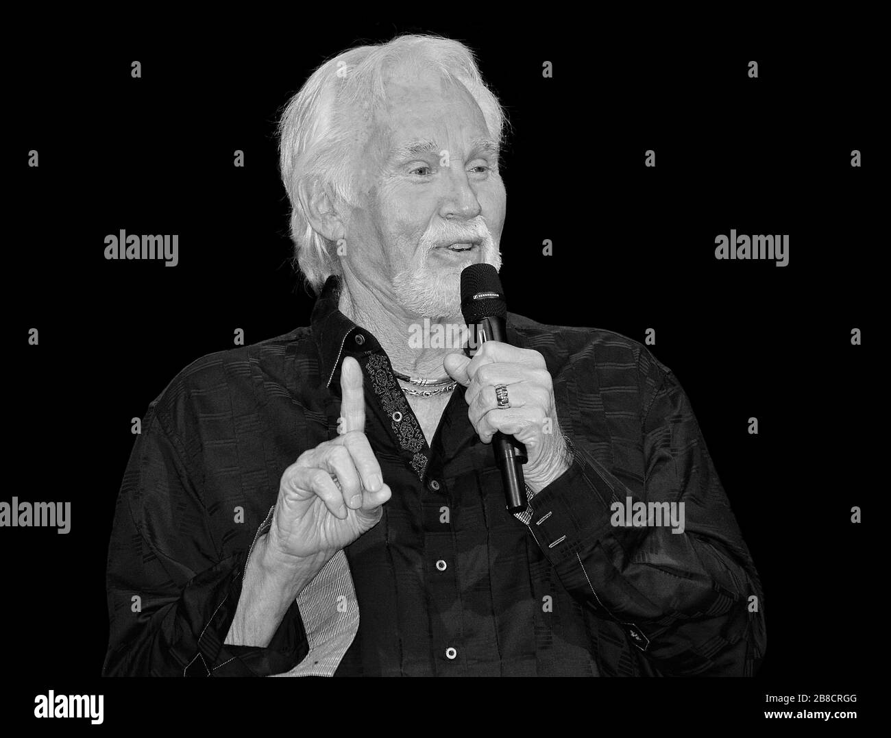 Portrait noir et blanc de Kenny Rogers avec microphone Banque D'Images