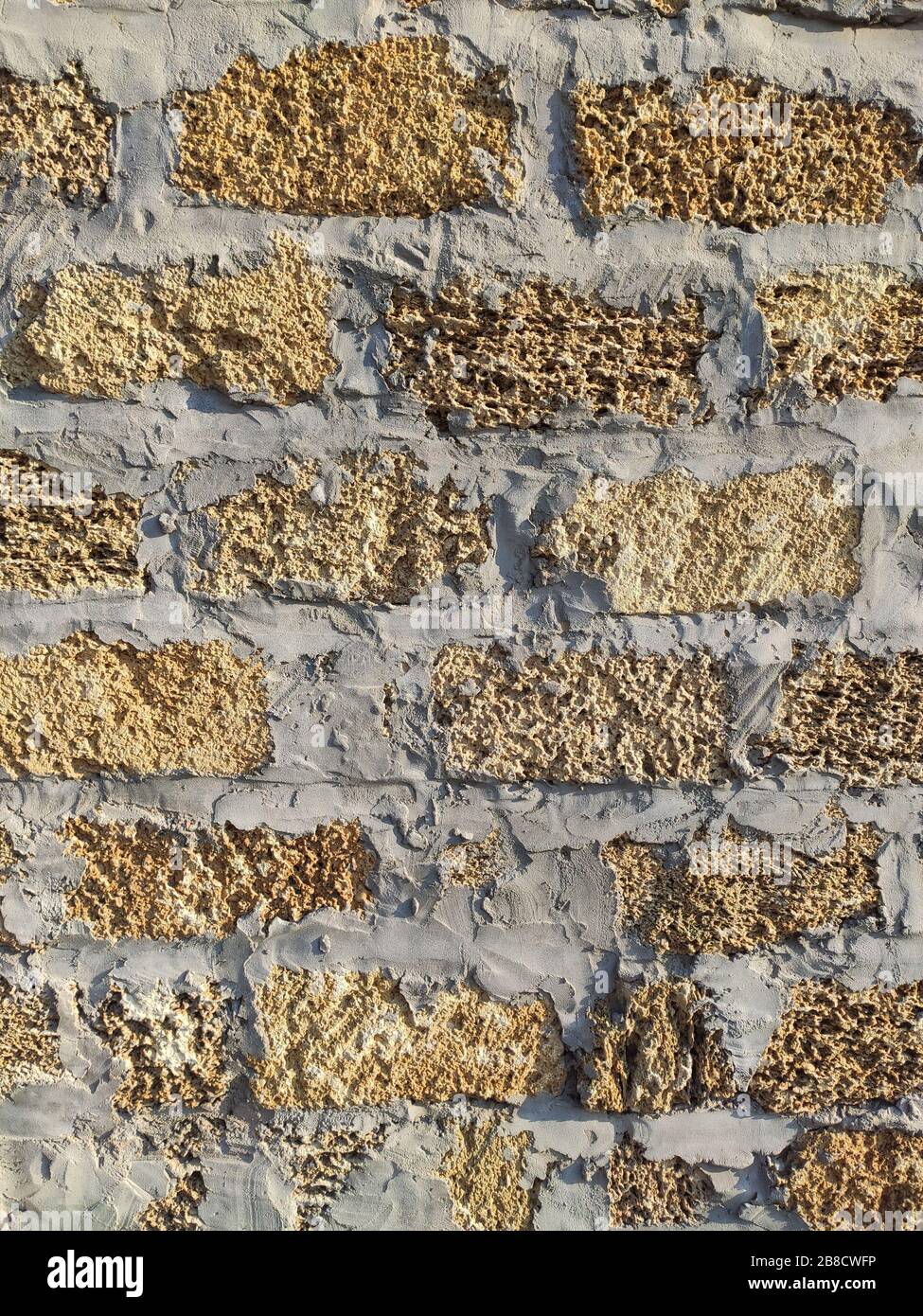 Ancienne texture de fond jaune brique. Mur de briques poreux dans le temple au coucher du soleil Banque D'Images
