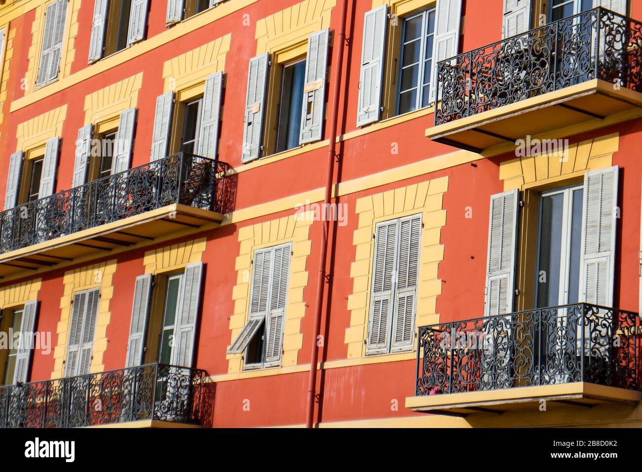 Façade orange typiquement colorée des bâtiments provençaux avec petits balcons en métal et volets colorés à Nice, Côte d'Azur, sud de la France. Banque D'Images