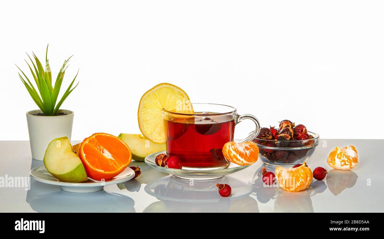Tasse avec infusion de rosehip, pomme, citron et mandarine sur une surface miroir. Banque D'Images