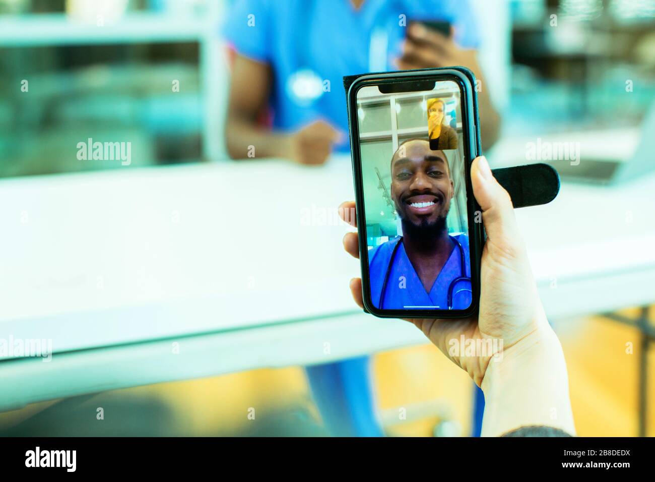 Portrait d'un patient malade toussant dans le tissu étant aidé par la télé médecine par un médecin de sexe masculin portant des gommages bleus uniforme à l'aide de smartphone mobile pH Banque D'Images