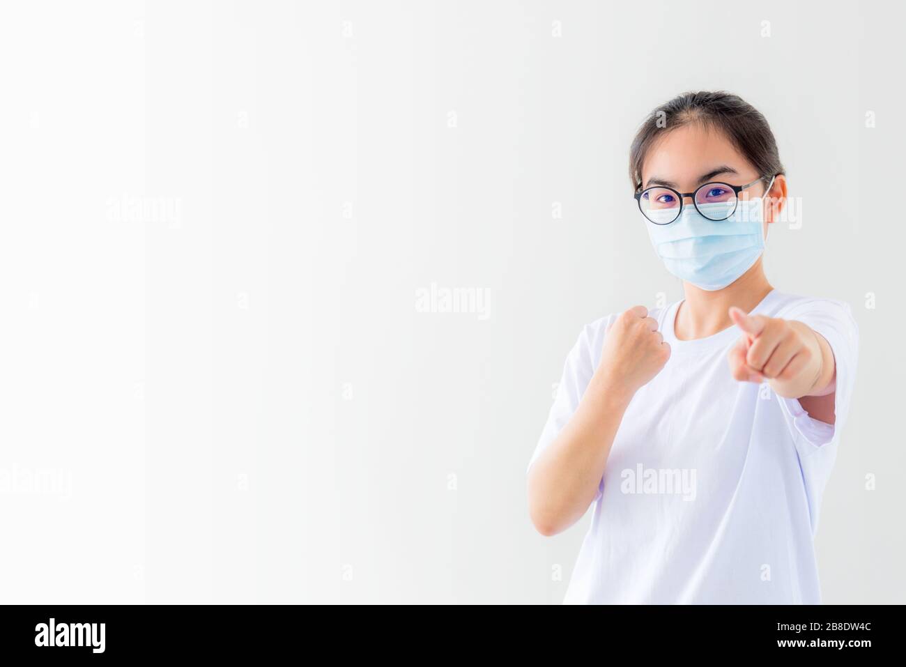 Portrait la jeune femme asiatique porte un masque pour se protéger contre le coronavirus, la jeune fille lève le poing et le doigt encourage la lutte contre la maladie contagieuse concept arrêter viru Banque D'Images