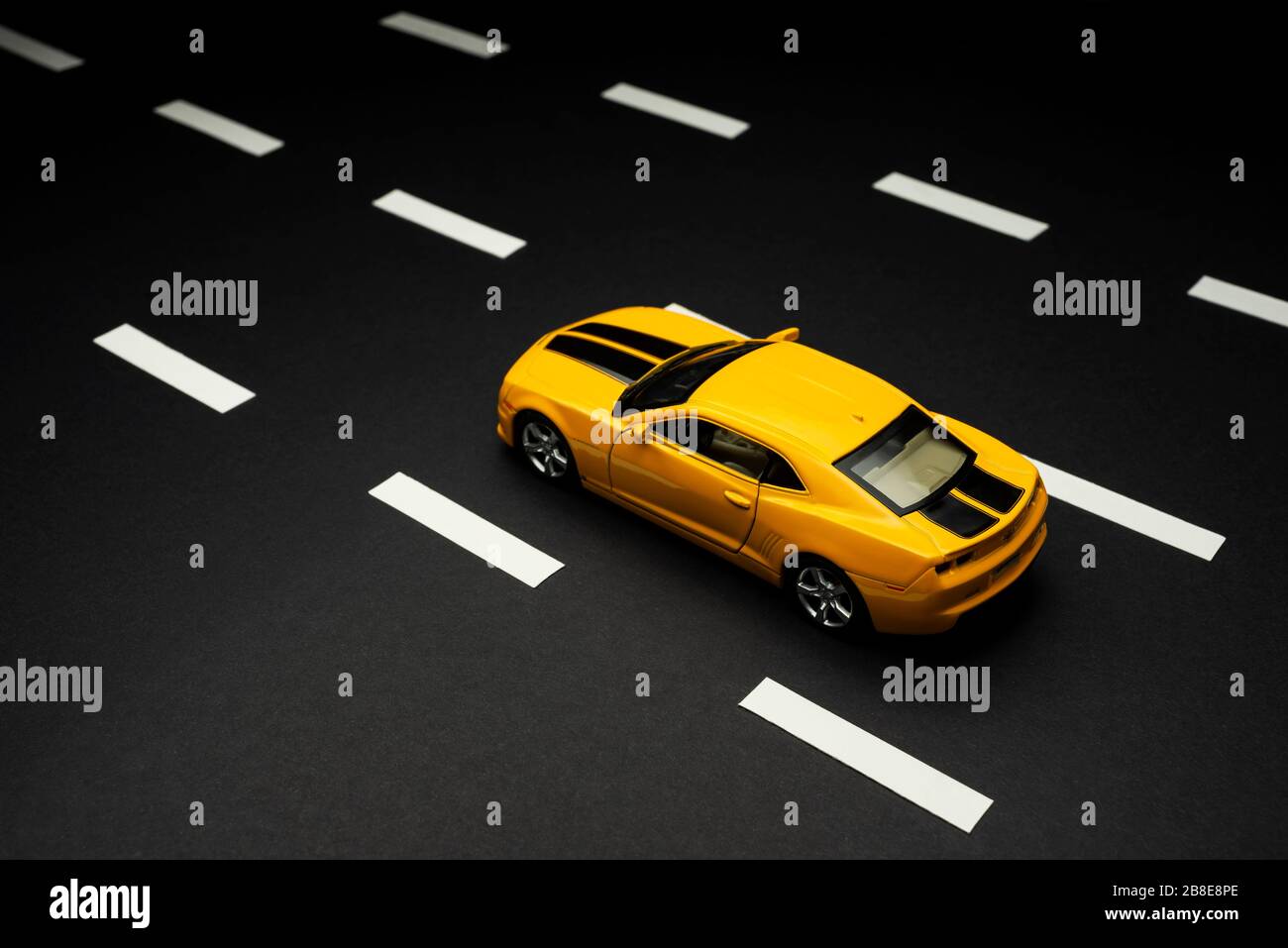 Izmir, Turquie - 28 juillet 2019: Vue de dessus et arrière d'une voiture de sport jouet jaune Chevrolet Camaro avec deux portes et bandes noires sur une route d'asphalte avec Banque D'Images
