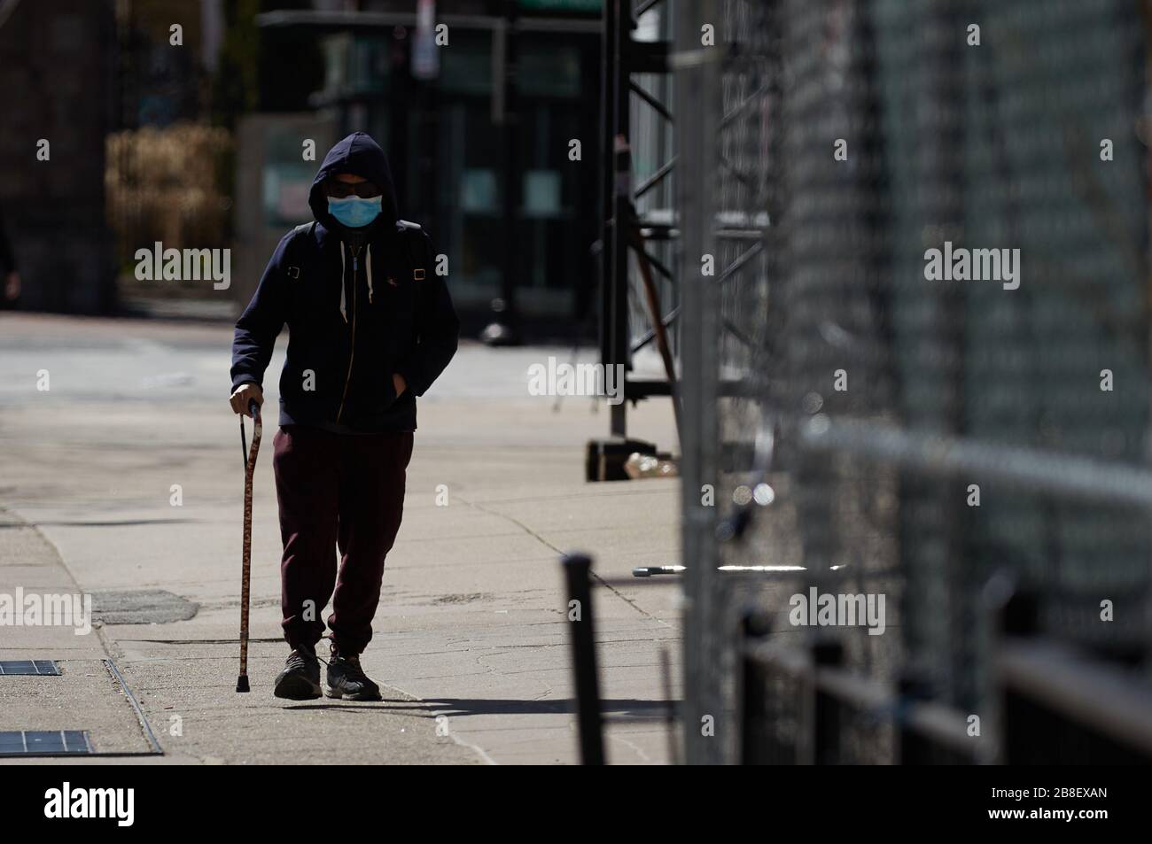 Boston, Massachusetts, États-Unis. 21 mars 2020. Le virus Corona, COVID-19, a provoqué un changement de vie dans le Massachusetts. Cela comprend un arrêt de la plupart des entreprises et une demande d'auto-quarantaine. Un homme descend dans la rue dans un masque. Crédit: Allison Dinner/ZUMA Wire/Alay Live News Banque D'Images