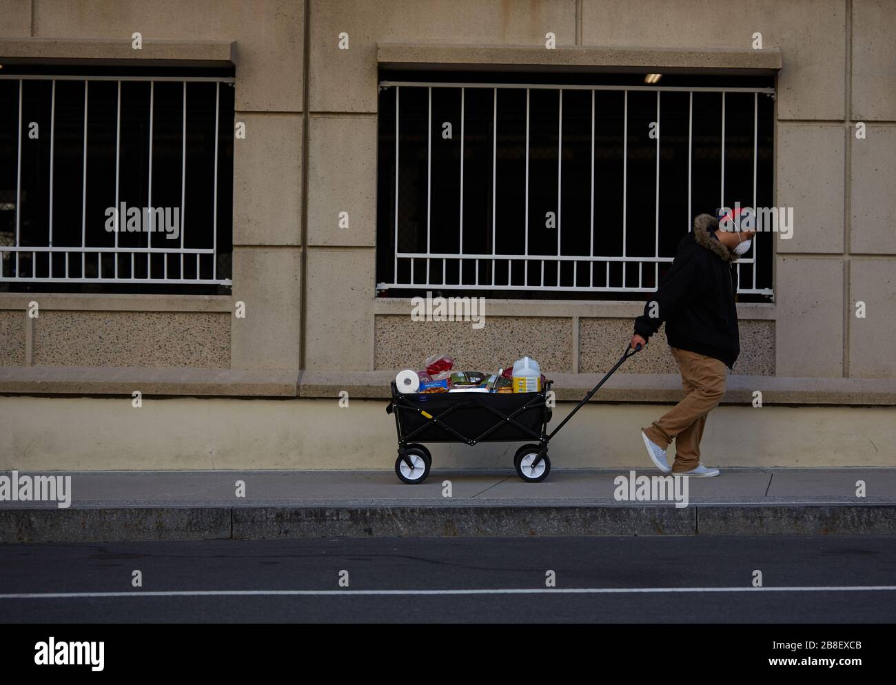 Boston, Massachusetts, États-Unis. 21 mars 2020. Le virus Corona, COVID-19, a provoqué un changement de vie dans le Massachusetts. Cela comprend un arrêt de la plupart des entreprises et une demande d'auto-quarantaine. Un homme descend la rue transportant des gelées dans un masque. Crédit: Allison Dinner/ZUMA Wire/Alay Live News Banque D'Images