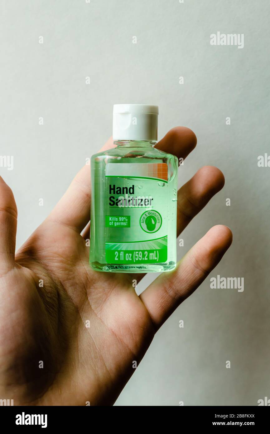Une petite bouteille de désinfectant pour les mains sans marque ni logo dans la paume d'une main caucasienne sur un fond blanc Banque D'Images