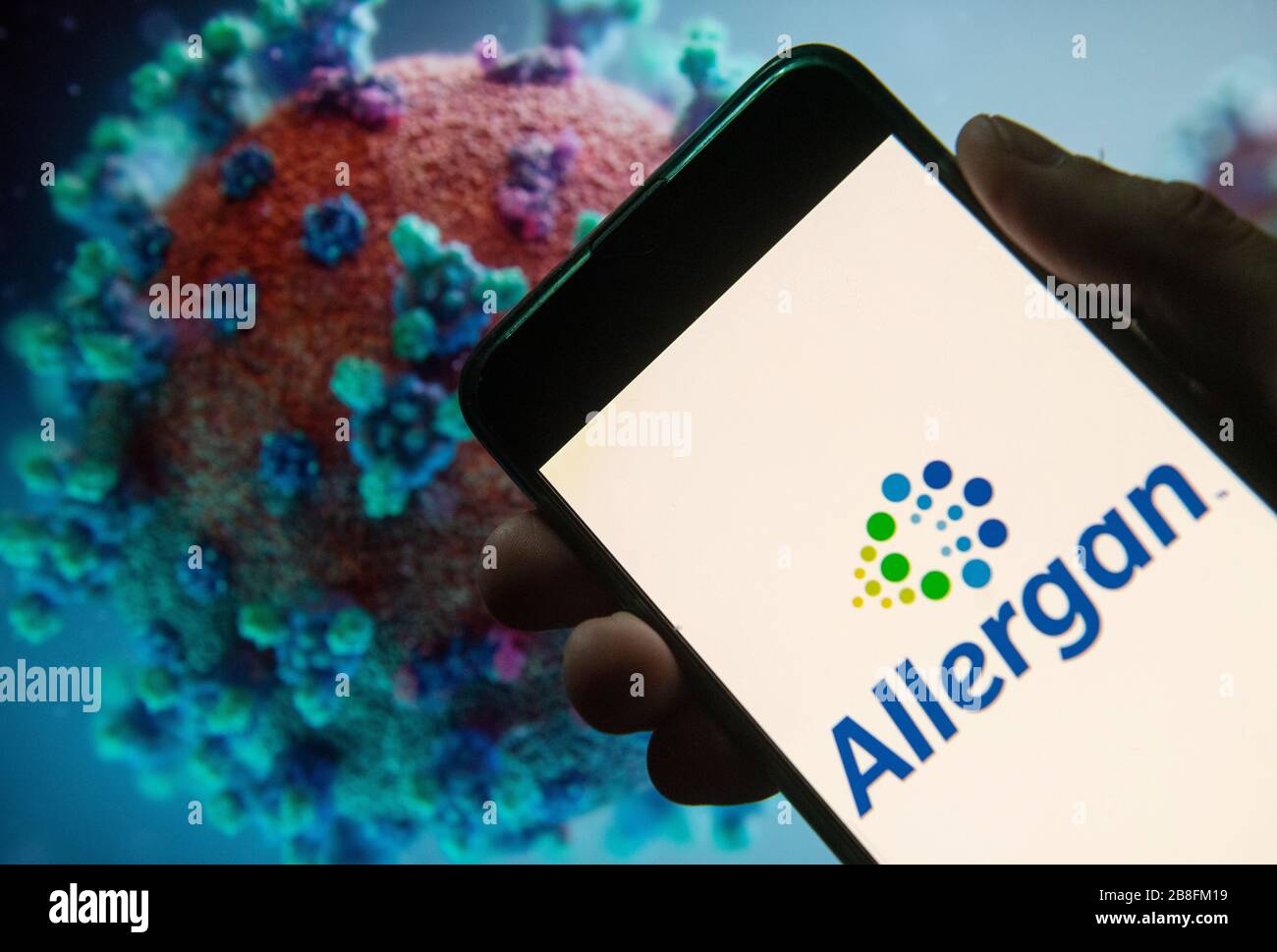 Dans cette illustration photo, le logo Allergan de la société pharmaceutique domiciliée en Irlande est affiché sur un smartphone avec un modèle informatique du coronavirus COVID-19 en arrière-plan. Banque D'Images