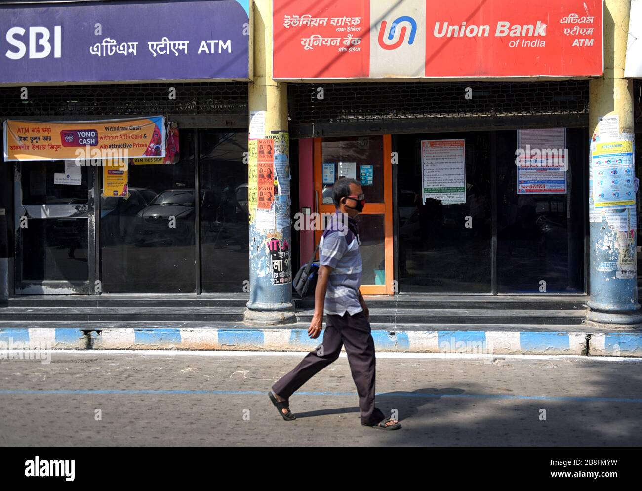 Un homme passe devant une banque de Sate DE L'INDE et des guichets automatiques de Union Bank à Kolkata. Banque D'Images