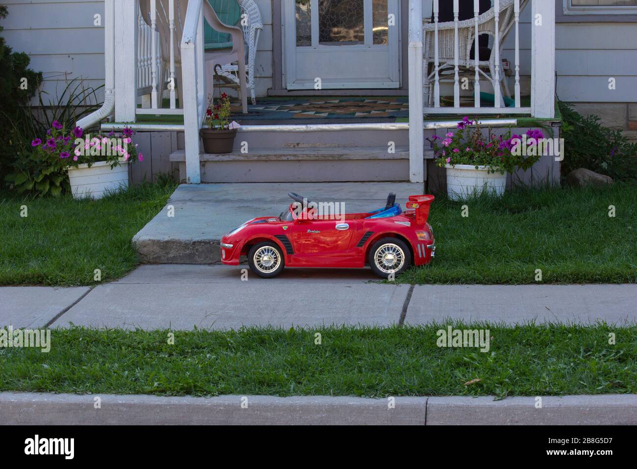 Voiture jouet rouge devant une petite maison de ville Banque D'Images