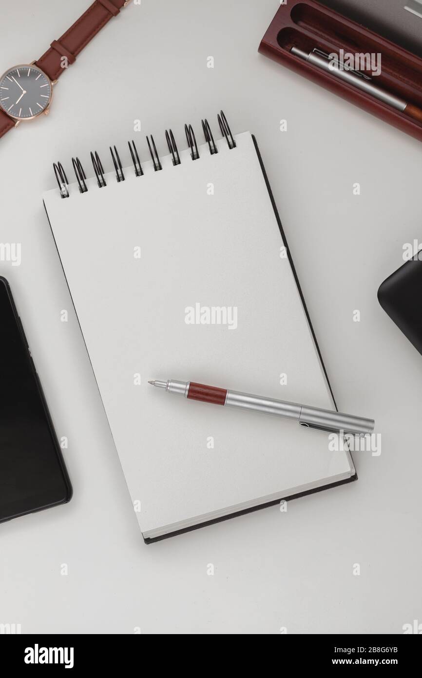 Arrière-plan minimaliste et détaillé de l'espace de travail, ordinateur portable en spirale ouvert avec feuille vierge, stylo et téléphone portable. Espace de copie vue de dessus, plat, maquette. Banque D'Images