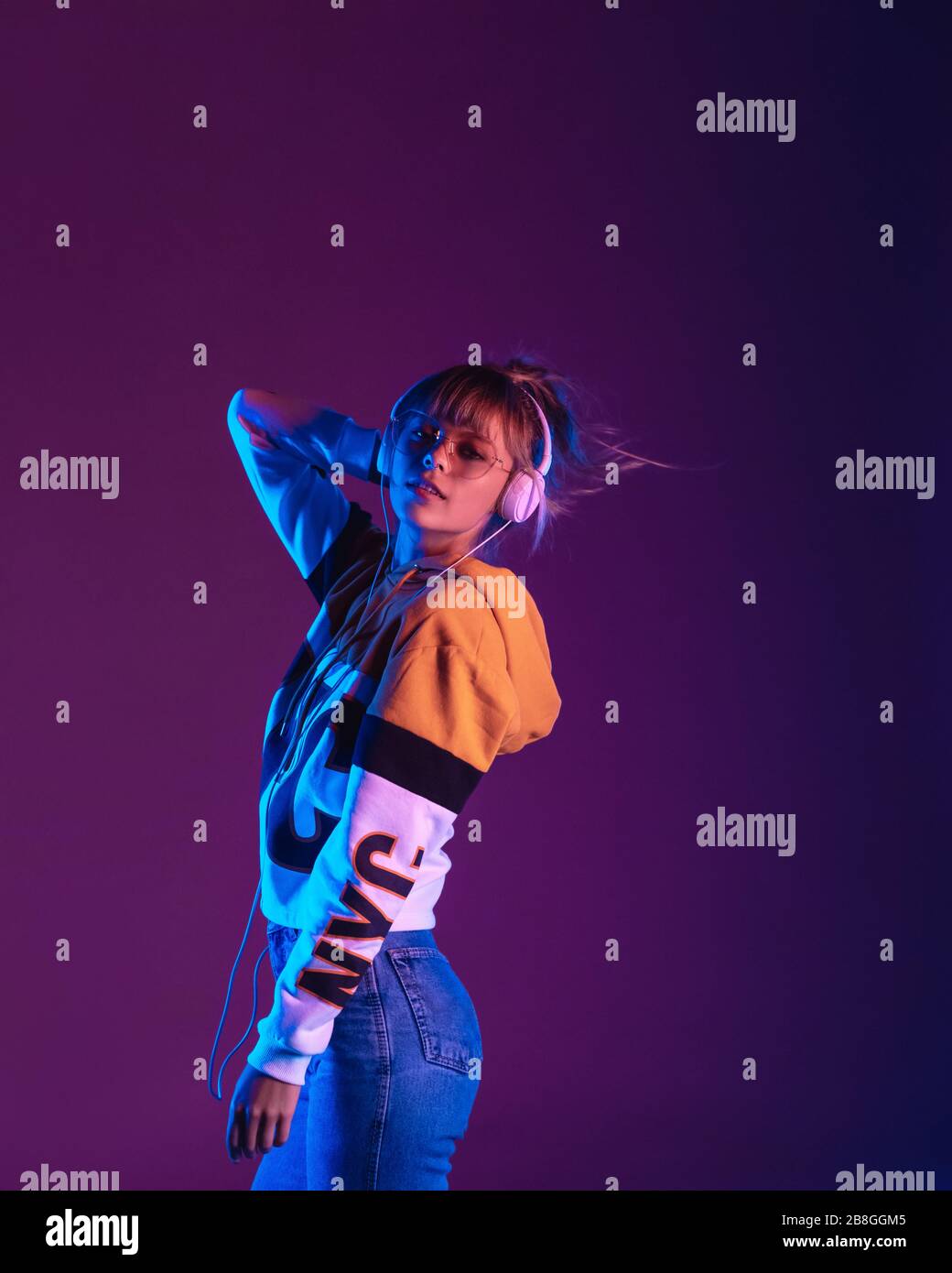 Élégante jeune fille porter lunettes écouteurs écoutez de la musique de danse, vertical. Banque D'Images