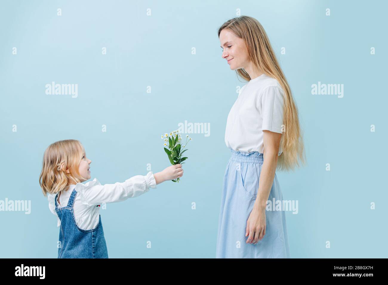 Petite fille donne à sa mère un bouquet de chamomilles sauvages. Les deux semblent heureux Banque D'Images