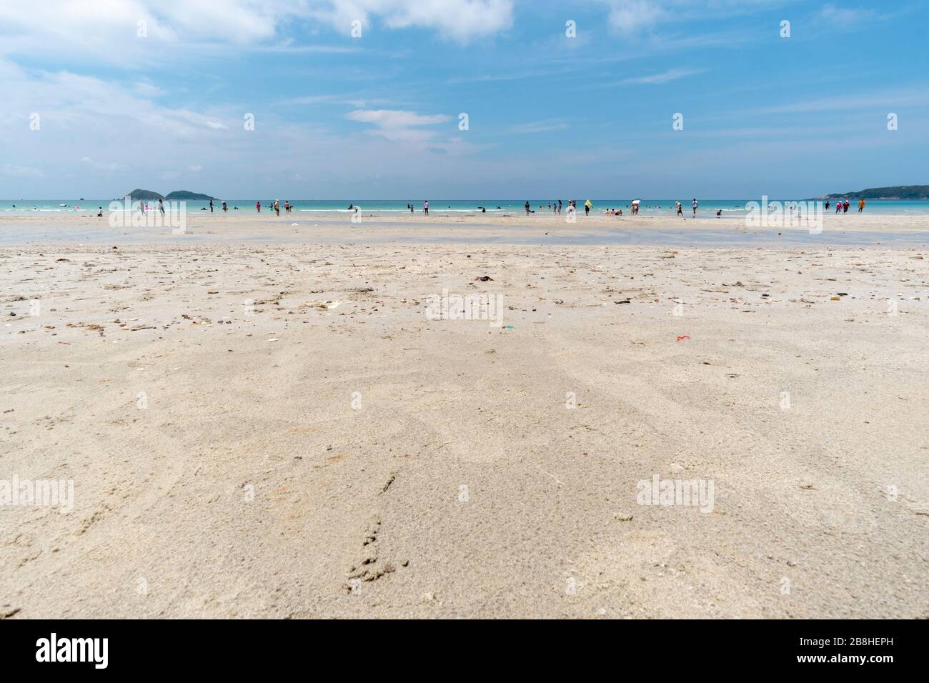 Les gens plongés dans la mer et se promènent sur le sable blanc. Banque D'Images