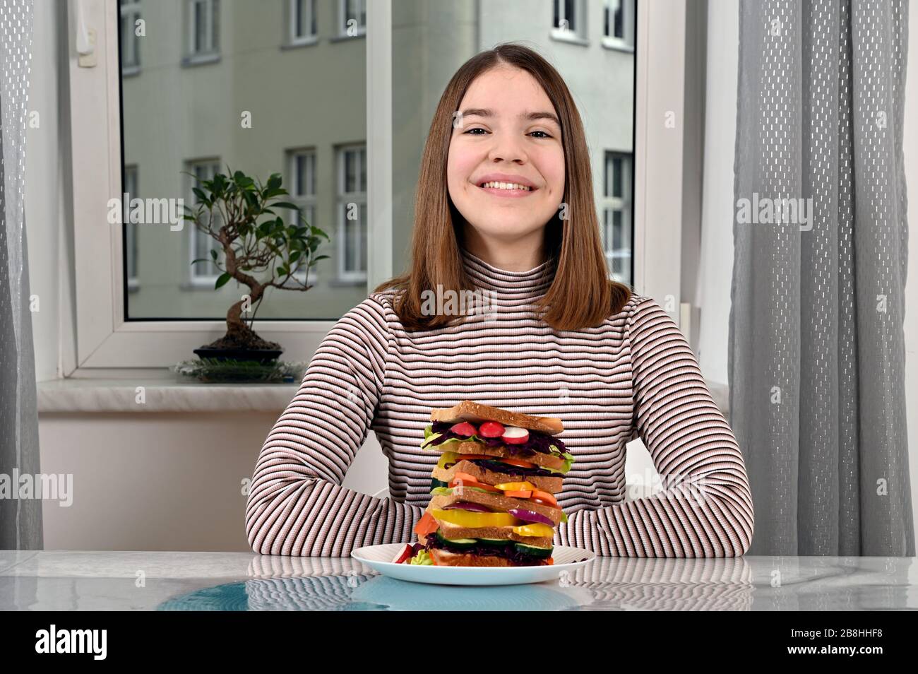 bonne fille adolescente avec sandwich végétarien à la maison Banque D'Images