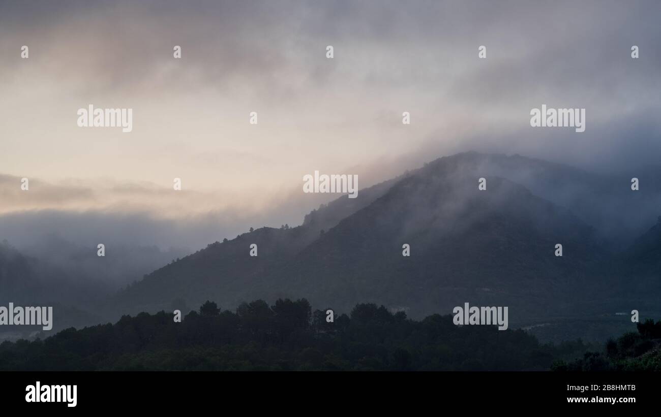 Une colline lointaine couverte de brouillard et de nuages bas Banque D'Images