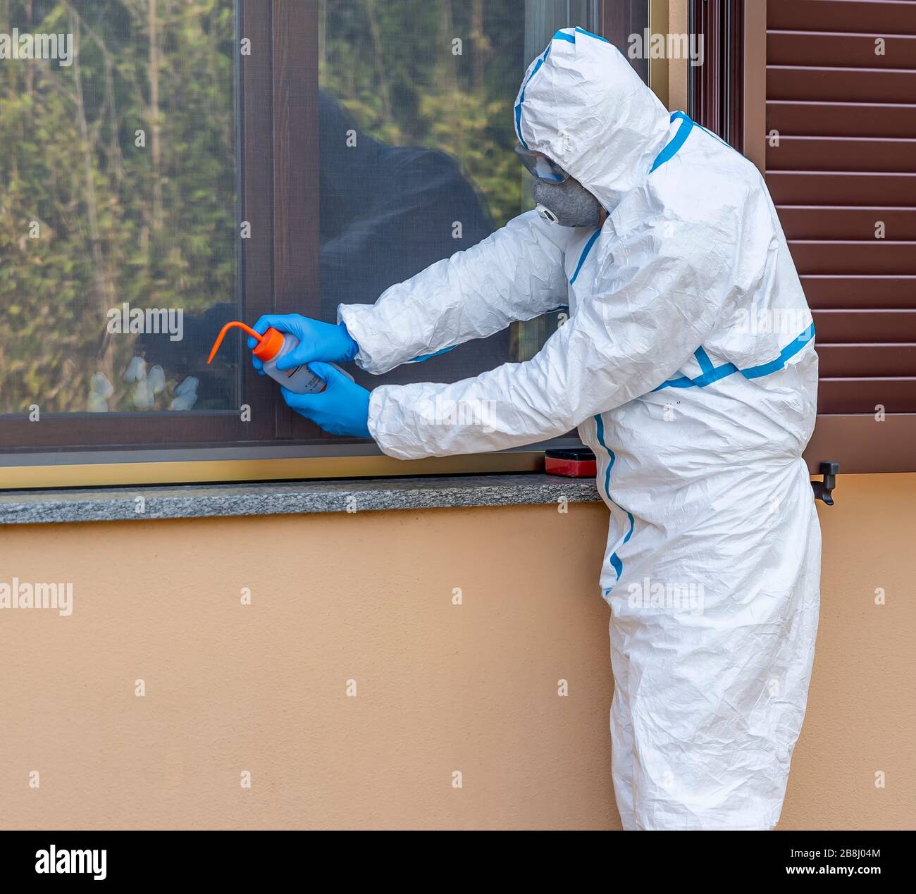 Le professionnel de la santé avec couverture blanche complète désinfecte d'éventuelles infections par le Coronavirus Covid-19 à l'aide d'une solution hydroalcoolique de pulvérisation Banque D'Images