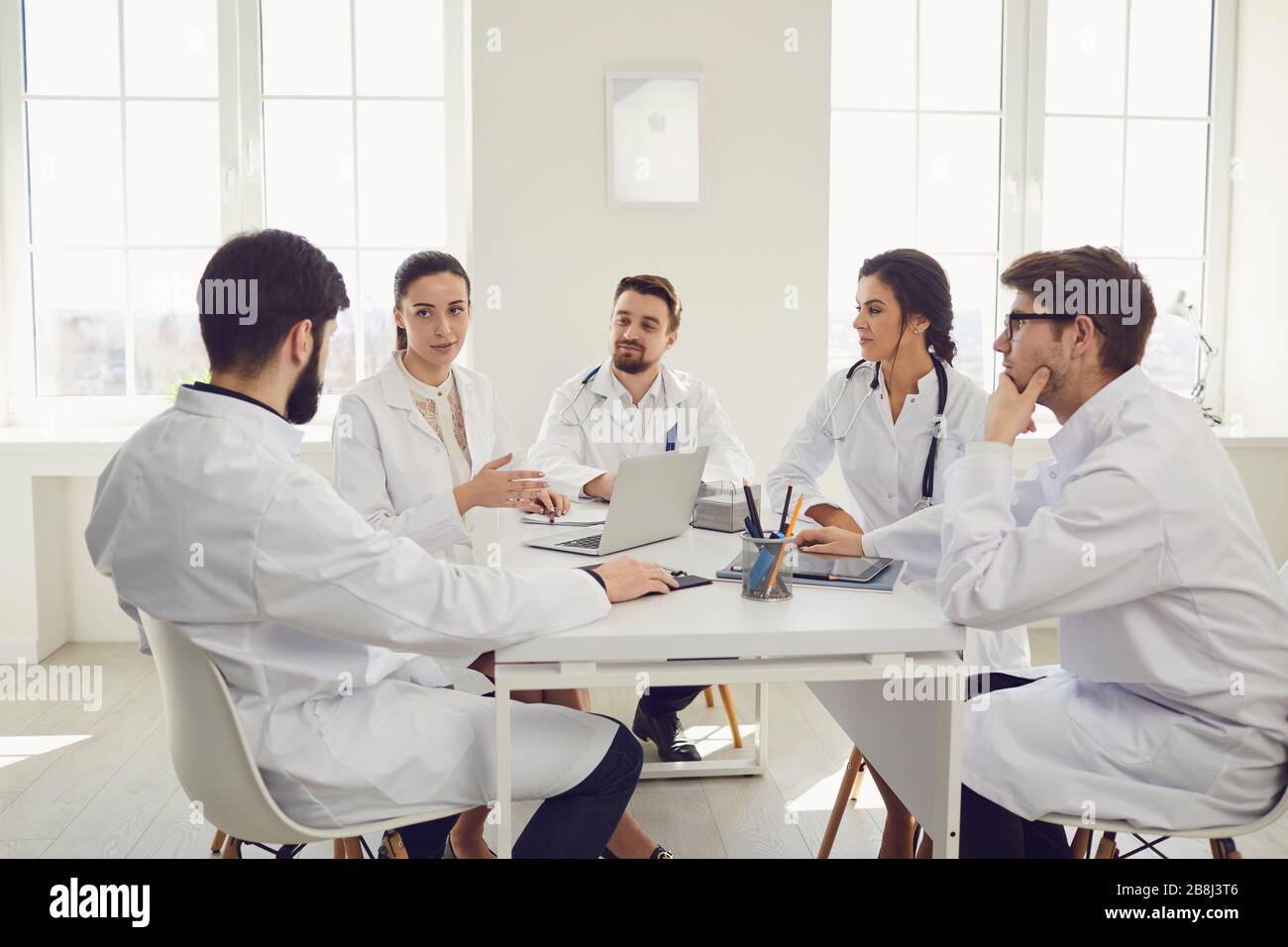Groupe de médecins praticiens lors d'une réunion discuter du diagnostic d'un patient debout dans un bureau de clinique. Banque D'Images