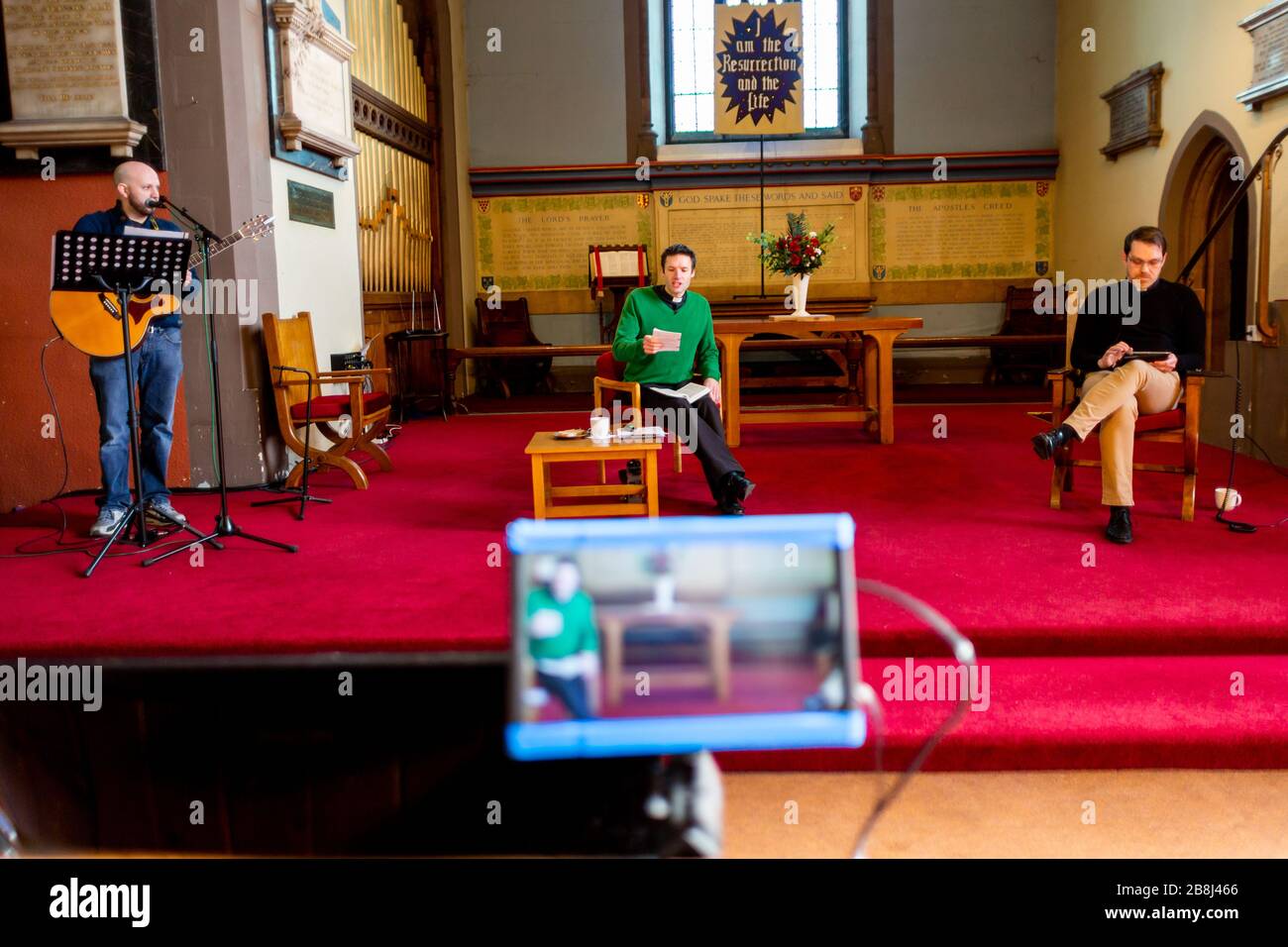 Cradley Heath, West Midlands, Royaume-Uni. 22 mars 2020. Pratiquer ce qui est prêché: Le révérend Nick Gowers se prépare à faire diffuser le service du dimanche matin de son église sur Youtube et son troupeau reste à l'intérieur. L'église de la Sainte Trinité a normalement une congrégation complète, mais mène des distanciation sociale avec seulement une poignée de volontaires techniques, avec le collègue de l'église Rich Hackett. Crédit: Peter Loppeman/Alay Live News Banque D'Images