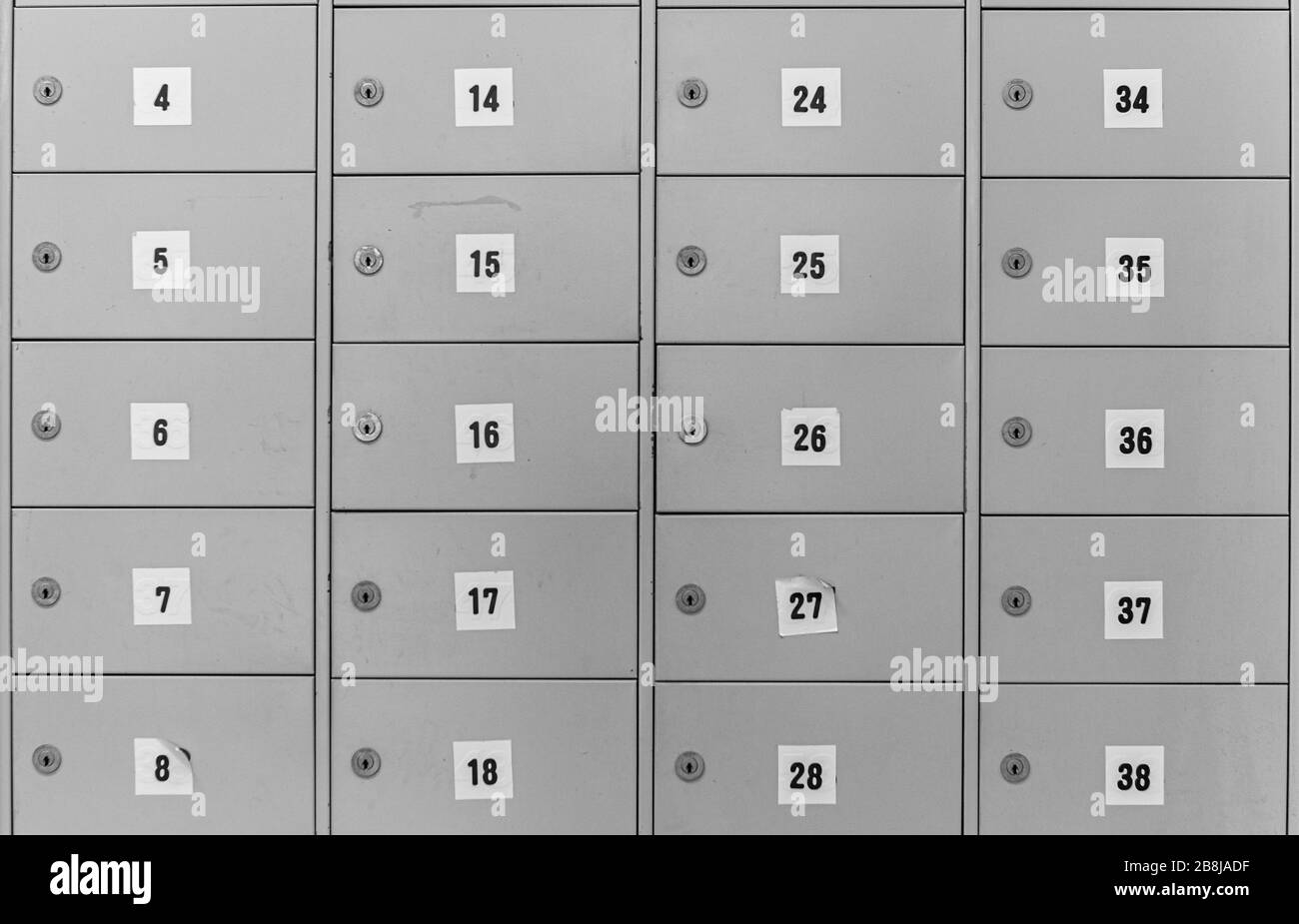 Image abstraite de boîtes métalliques verrouillées numérotées avec portes à charnières, disposées en grille. Banque D'Images