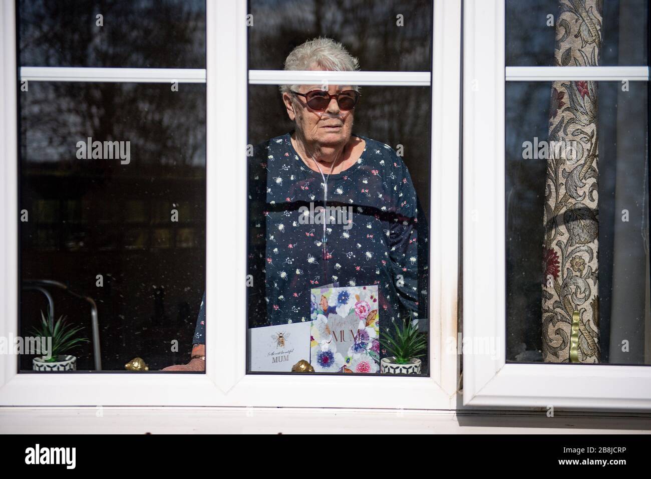 Olive Trotman, 76 ans, est visité le jour de la mère par son fils Mark Trotman. L'olive souffre de la maladie pulmonaire obstructive chronique (MPOC) et de l'emphysème, et prend la précaution de communiquer à une distance sûre ou à travers une fenêtre de verre, afin de limiter la propagation potentielle du coronavirus. Date de la photo Dimanche 22 Mars 2020. Voir l'histoire de PA SANTÉ Coronavirus. Crédit photo devrait lire: Jacob King/PA fil Banque D'Images