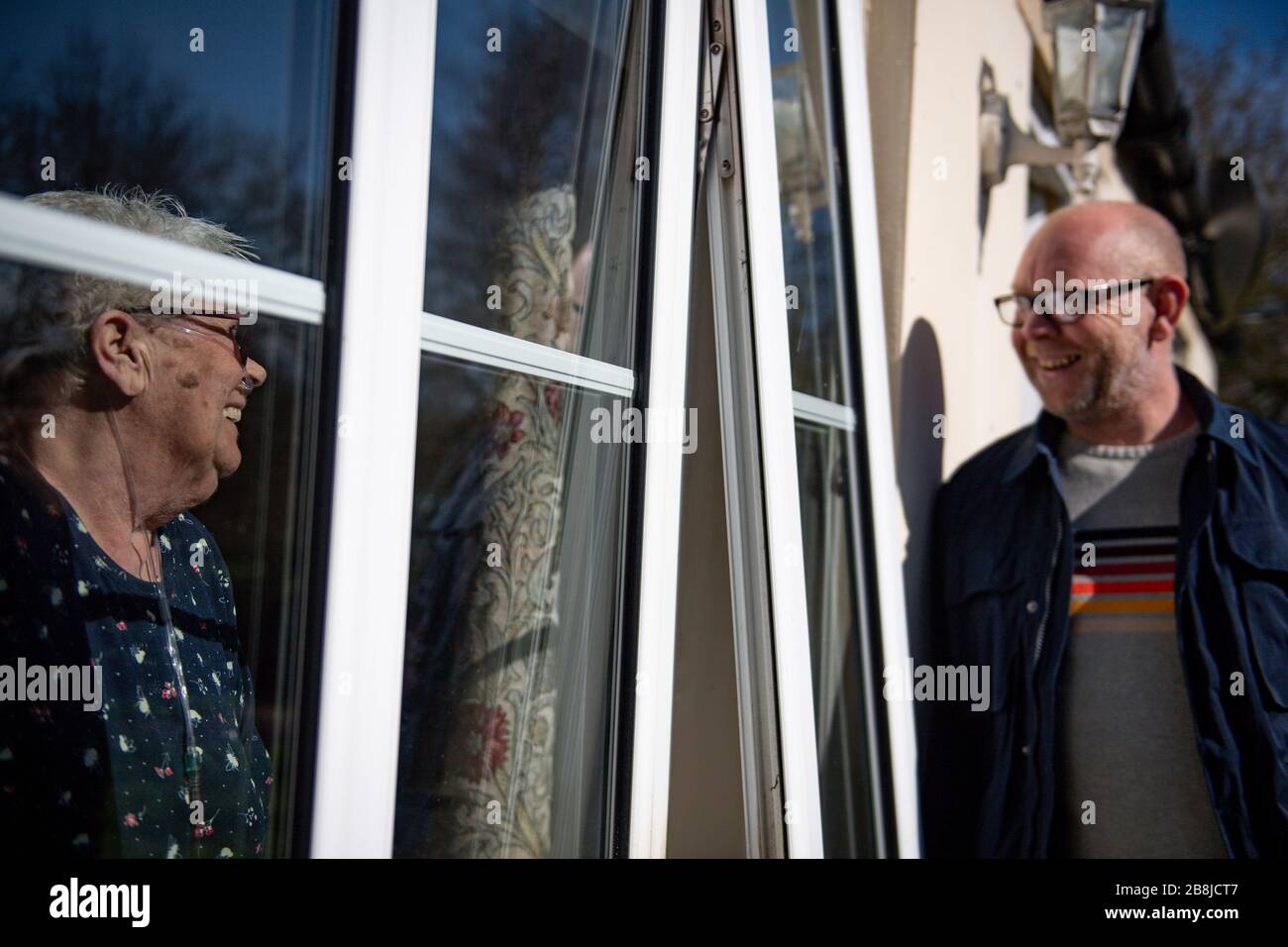 Olive Trotman, 76 ans, est visité le jour de la mère par son fils Mark Trotman. L'olive souffre de la maladie pulmonaire obstructive chronique (MPOC) et de l'emphysème, et prend la précaution de communiquer à une distance sûre ou à travers une fenêtre de verre, afin de limiter la propagation potentielle du coronavirus. Date de la photo Dimanche 22 Mars 2020. Voir l'histoire de PA SANTÉ Coronavirus. Crédit photo devrait lire: Jacob King/PA fil Banque D'Images