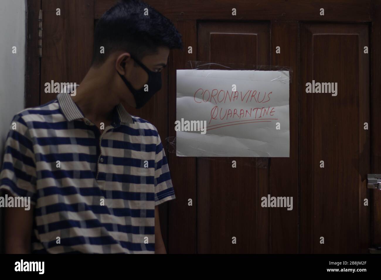 Coronavirus infecté Italien homme portant le masque de visage à la maison quarantaine avec le signe de quarantaine du coronavirus dans la porte.patient de Coronavirus à la maison qquaran Banque D'Images