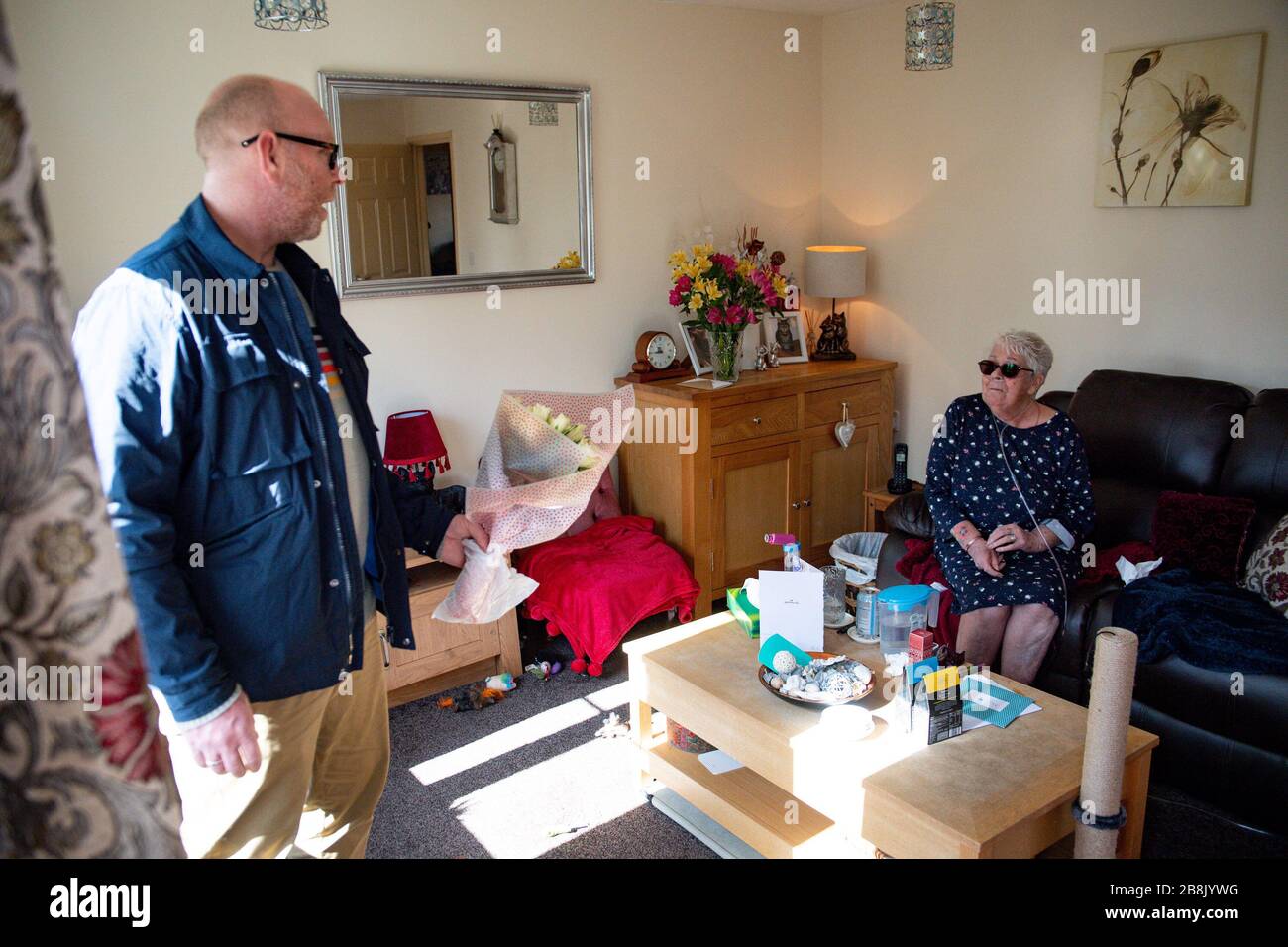 RETRANSMIS PAR L'AJOUT DE LIEU Olive Trotman, 76 ans, est visité le jour de la mère par son fils Mark Trotman à Napton sur la colline, Warwickshire. L'olive souffre de la maladie pulmonaire obstructive chronique (MPOC) et de l'emphysème, et prend la précaution de communiquer à une distance sûre ou à travers une fenêtre de verre, afin de limiter la propagation potentielle du coronavirus. Banque D'Images