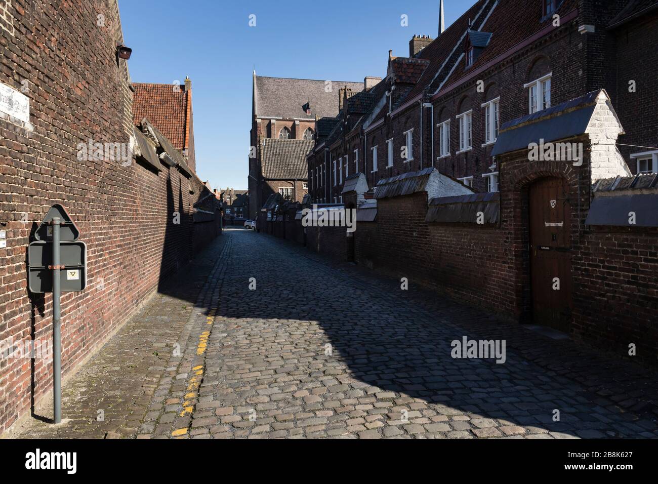 Gent, Belgique - 22 mars 2020: Allée dans le Beguinage Saint Elisabeth ou Groot Begijnhof .rue pavée. Mur de briques Banque D'Images