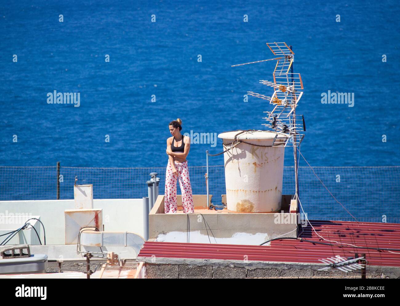 Las Palmas, Grande Canarie, îles Canaries, Espagne. 22 mars 2020. Alors que l'Espagne termine sa première semaine d'un maintien strictement imposé, une femme prend le soleil depuis le toit surplombant l'océan Atlantique sur Gran Canaria. Le Premier ministre espagnol a annoncé dimanche que l'état d'urgence du dispositif de verrouillage/de quarantaine de Coronavirus serait prolongé jusqu'au 12 avril au plus tard. En dehors de l'Italie, l'Espagne a le taux d'infection/décès le plus élevé de Covid-19 en Europe. Crédit: Alan Dawson/Alay Live News Banque D'Images