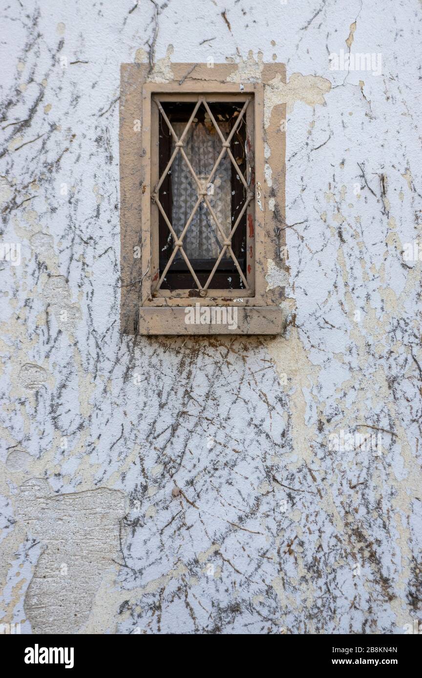 La façade avec des restes de végétation commune ivy sont endommagés par le plâtre et la peinture et les petites fenêtres en bois avec des barres de fenêtre comme protection de cambriolage Banque D'Images