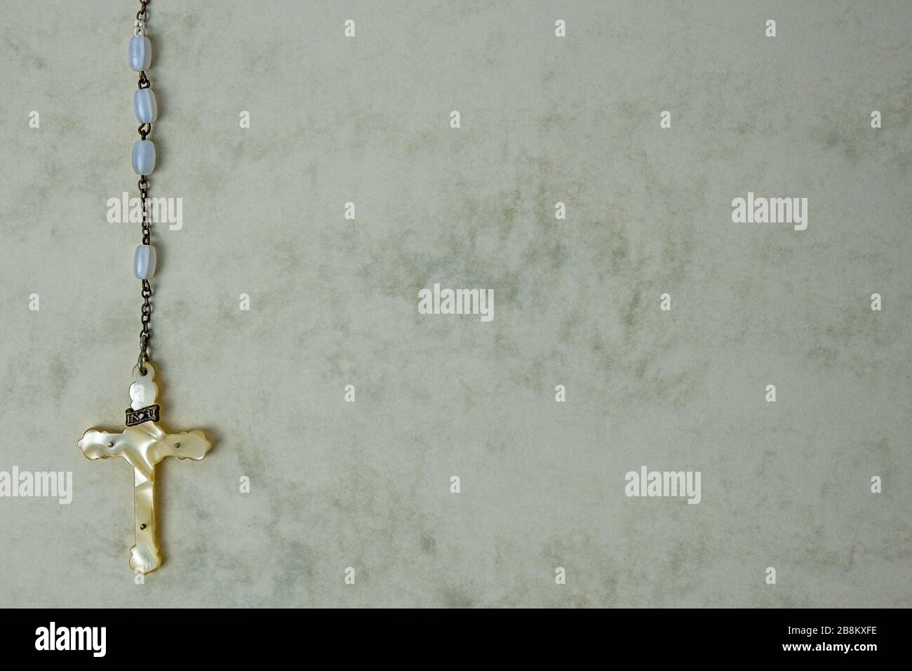 Partie inférieure d'un rosaire avec une croix sur un fond marbré, beaucoup d'espace libre pour le texte Banque D'Images