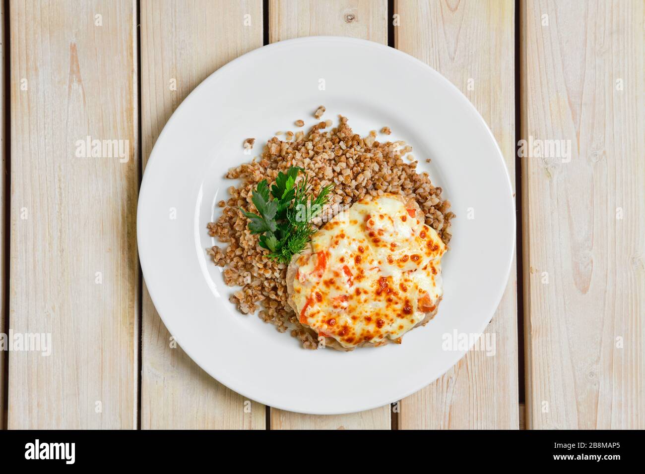 Vue de dessus de la viande de porc hachée cuite au fromage et à la tomate servie avec du porridge de sarrasin Banque D'Images