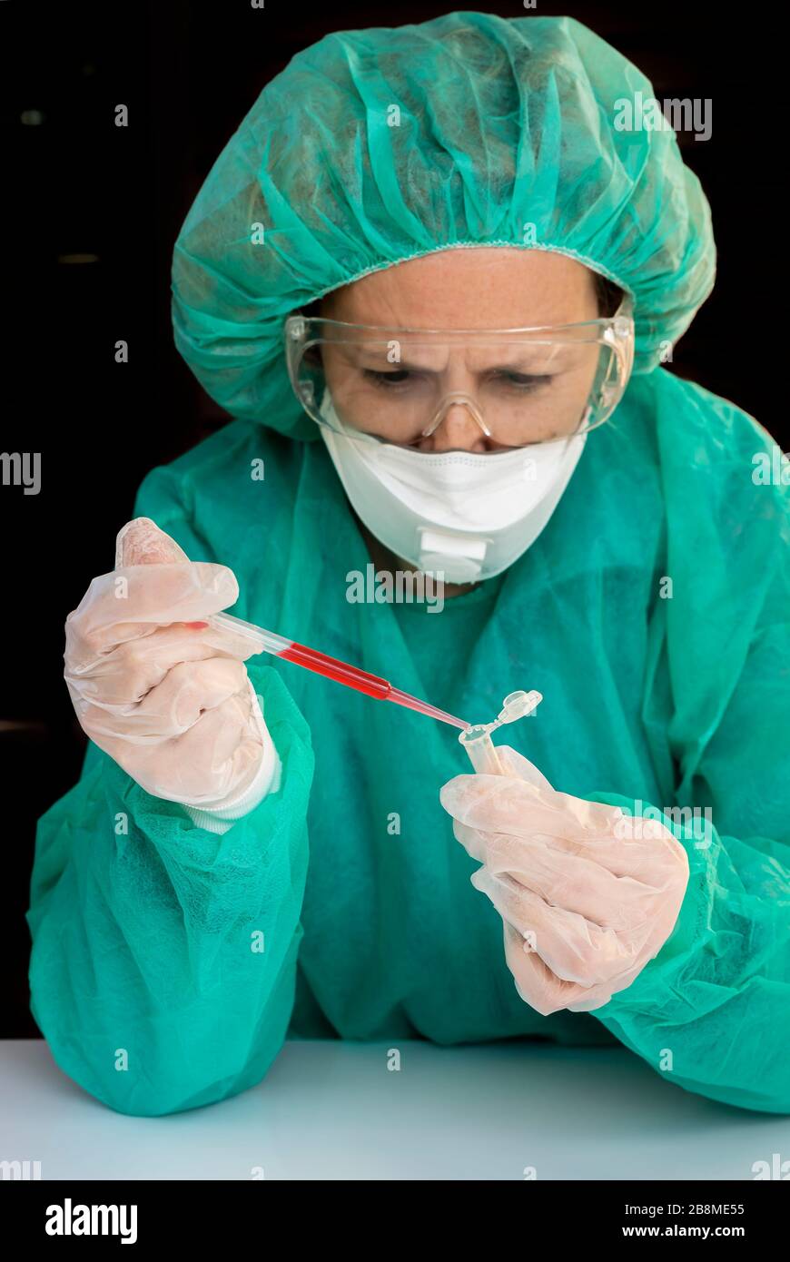 Un technicien de laboratoire doté d'un capuchon de protection pour les cheveux, le masque, les lunettes et les gants effectue une analyse eppendorf pour vérifier la contagion du Coronavirus Covid-19 Banque D'Images