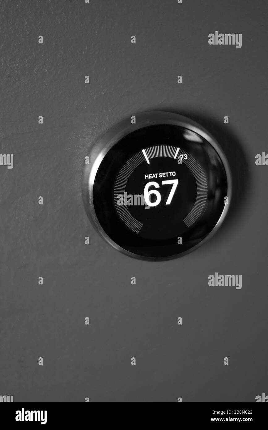Thermostat domestique nid noir et blanc isolé sur le mur. Aucun corps, personne n'est présent. Technologie verte Banque D'Images