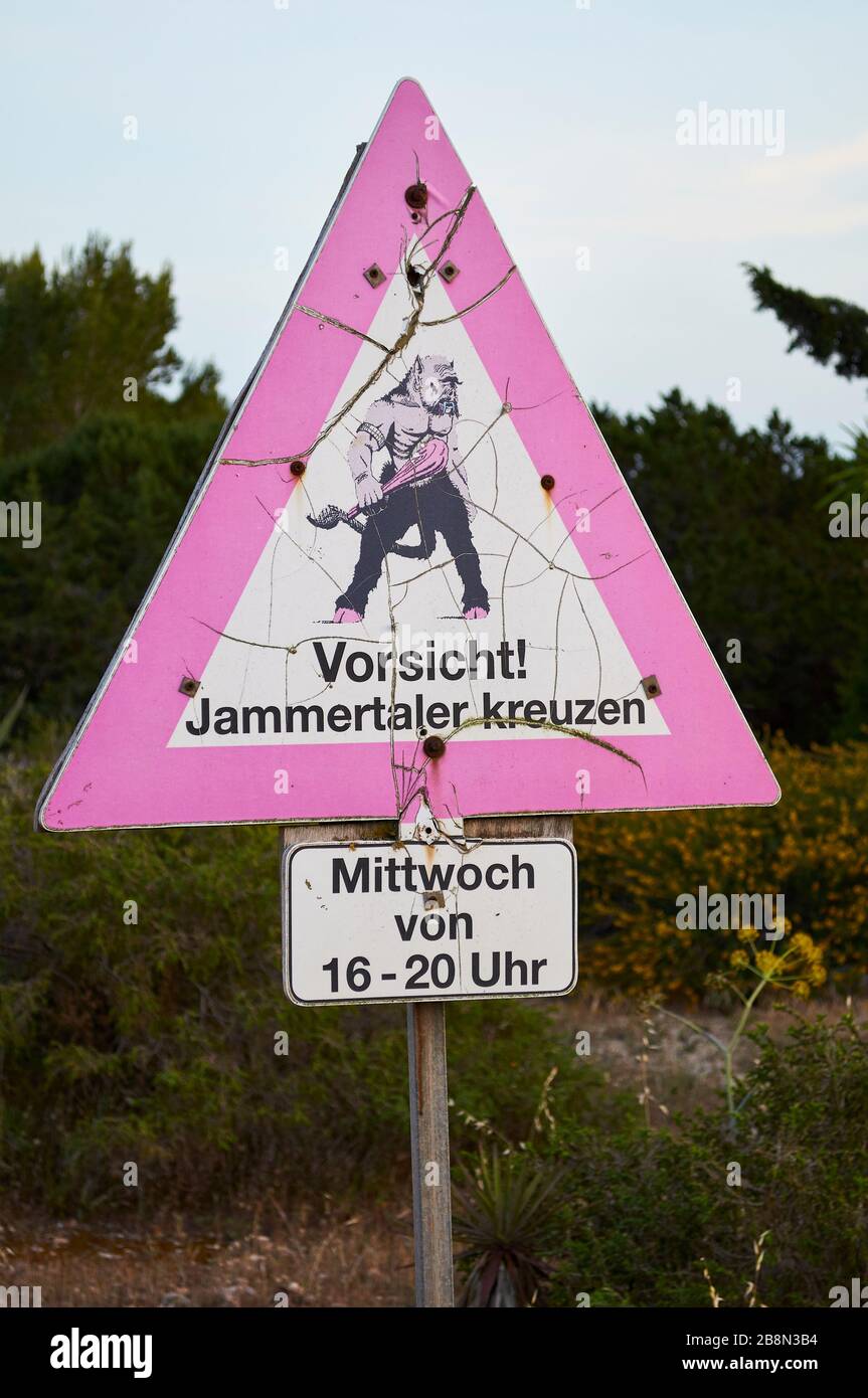 Étrange artistique étrange drôle de mise en garde signpost avec Vorsicht Word et cyclop avec la mace dans le parc naturel de ses Salines (Formentera, Iles Baléares, Espagne) Banque D'Images